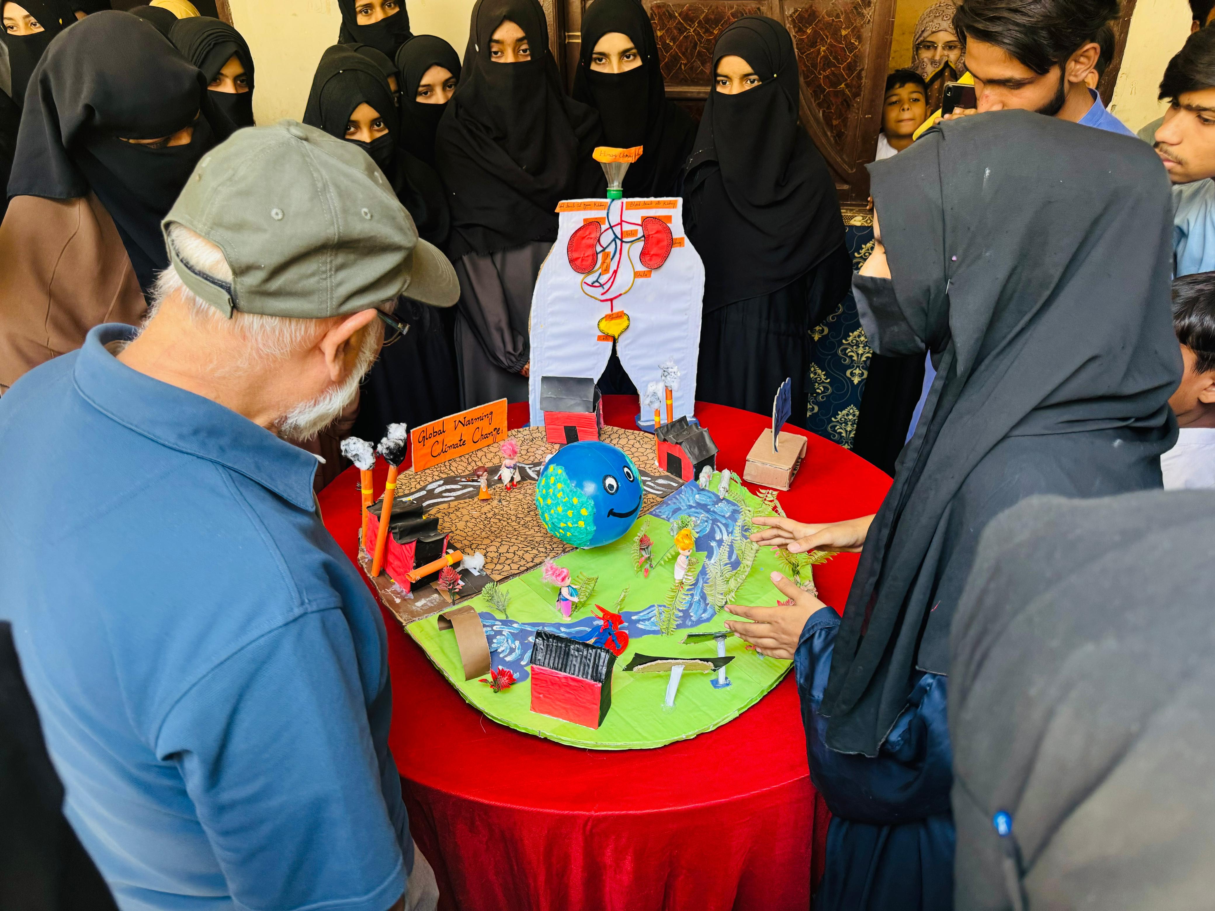 School group observing a science project display, supported by the Islamic charity USA.