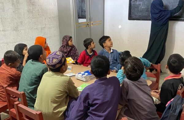 Students in chairs are attentively listening to the teacher.