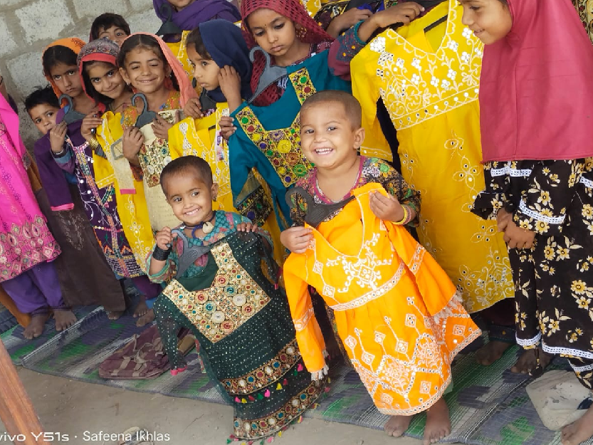 Vulnerable students in Eshaat school showing dresses received as an Eid gift.