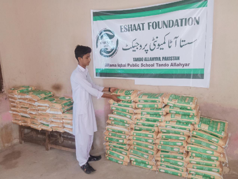 A vulnerable person receiving aid in front of a banner of Eshaat Foundation.