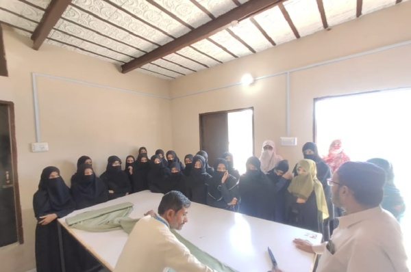 Students and the teacher are standing to conduct a practical class on stitching.