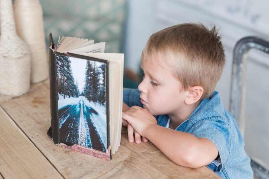 A small boy reading story book as an Eid gift.